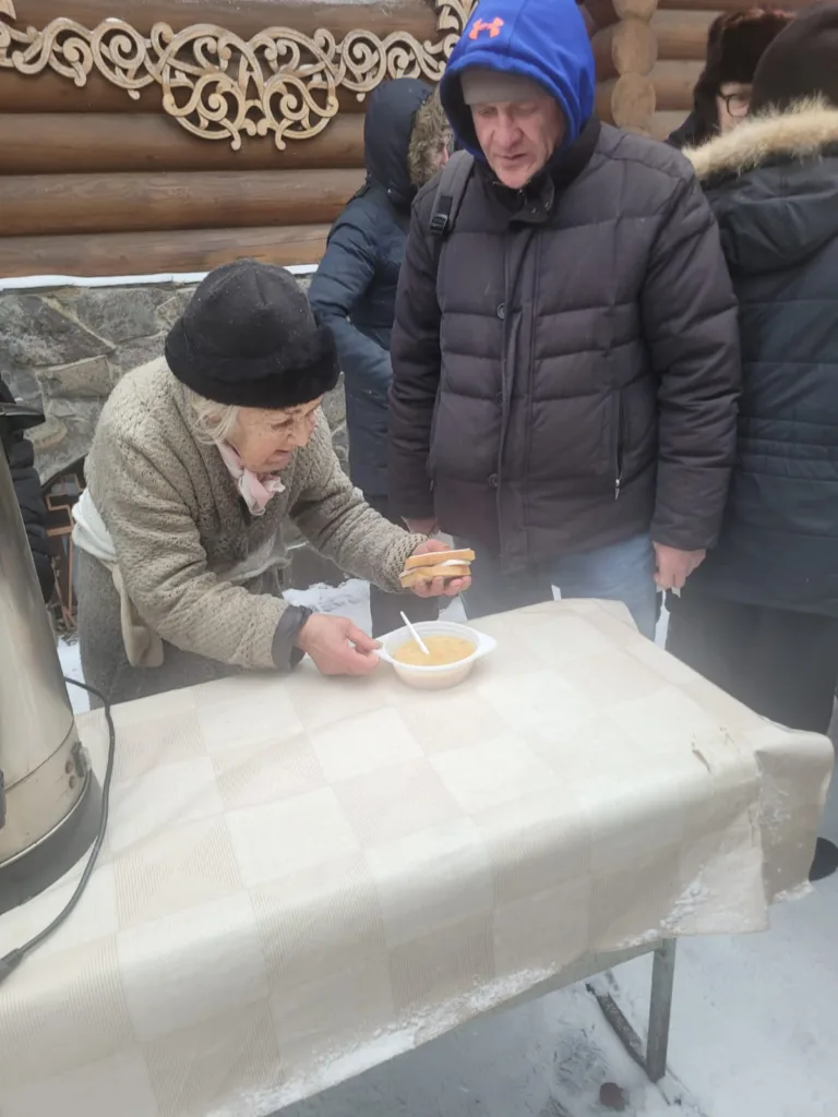 zhinka v shaptsi i palto bilja stolu